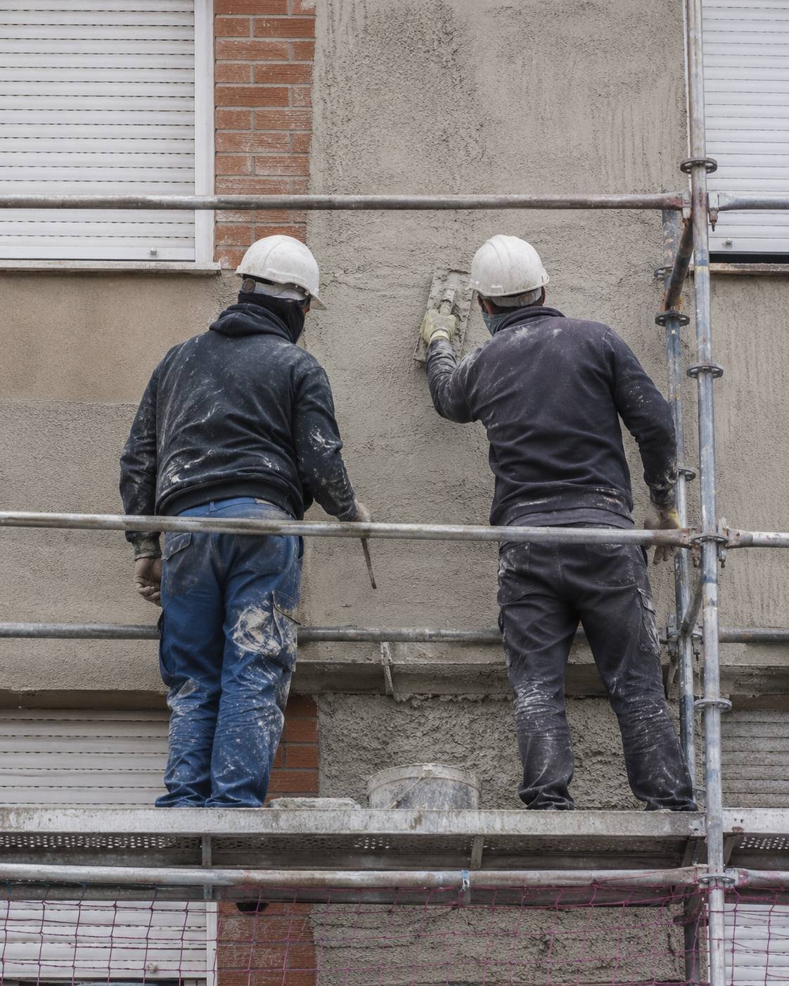 Operarios trabajando sobre el andamio de una fachada en rehabilitación