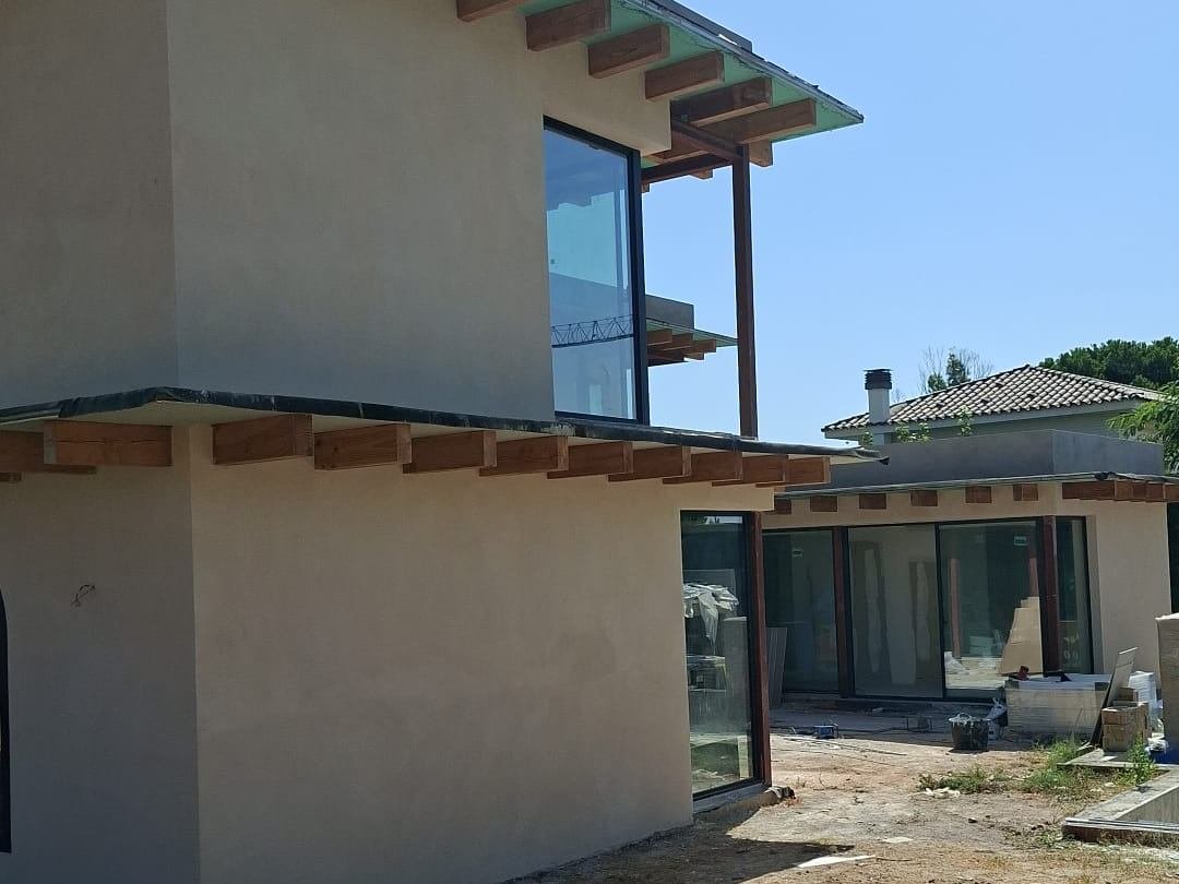 Otro frente de la misma vivienda de El Masnou, con el revoco de cal aplicado y el vuelo del alero sobre las vigas de madera