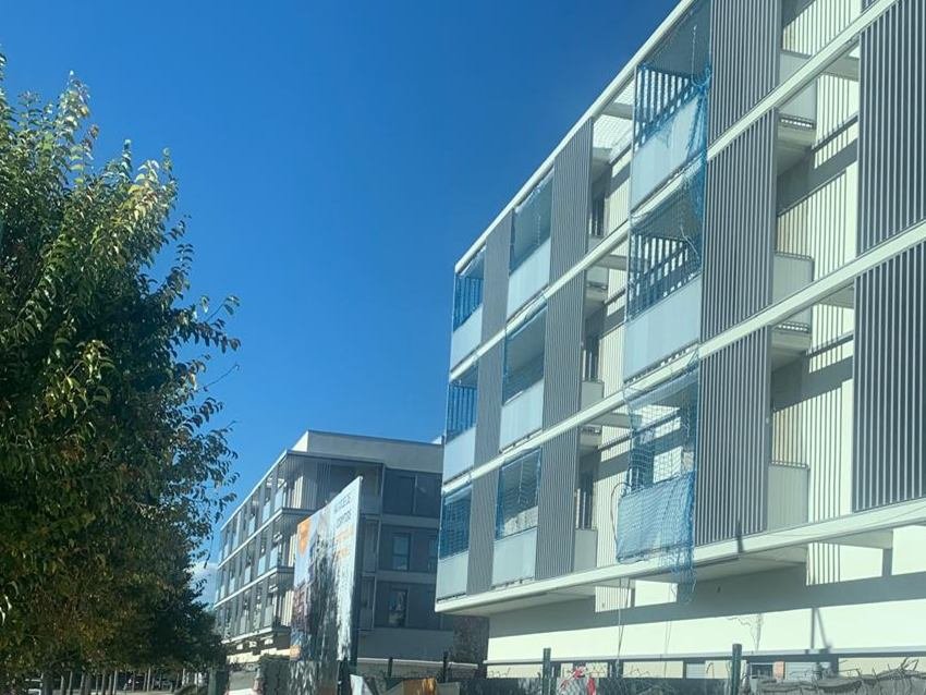 Bloque de viviendas en Girona con la fachada terminada en mortero acrílico claro, lamas verticales de protección y frentes de balcón continuos