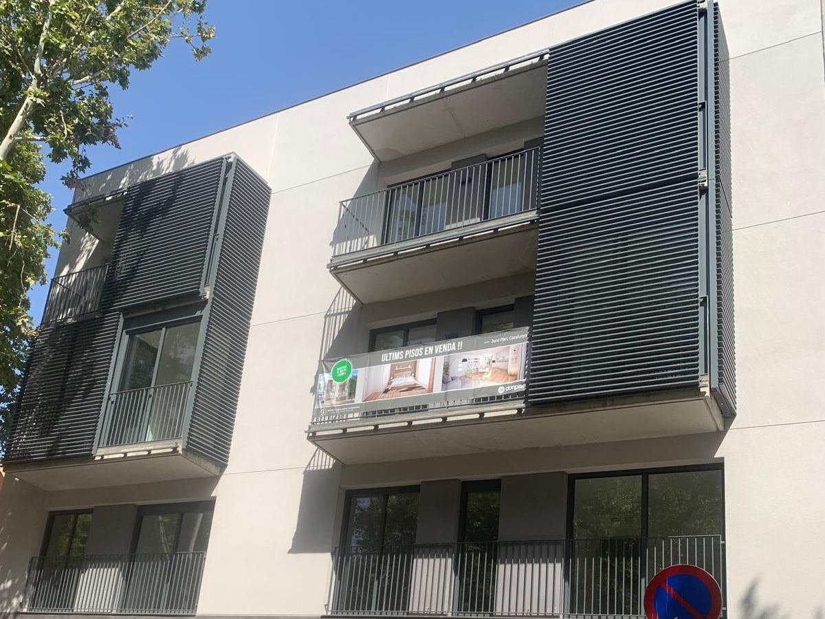 La misma fachada de Sabadell vista de frente, con el mortero monocapa en tono claro, los balcones y las lamas de protección solar plegadas